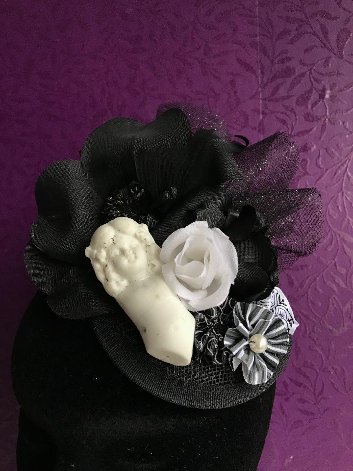 IMAGE - Black sinamay fascinator with antique porcelain doll, vintage black and white flowers, black glittertulle, and ribbon rosettes. Fixes to the hair with a comb.