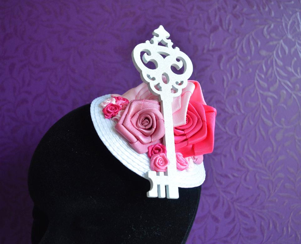 IMAGE - White fascinator decorated with pink ribbon roses and white glittered key.
Fixes to hair with a comb.