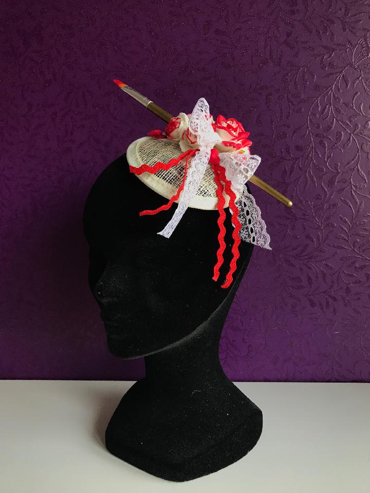 IMAGE - Cream sinamay fascinator with paintbrush, half painted white roses and white lace bow. Finished with red satin hearts.
Fixes to the hair with a comb.