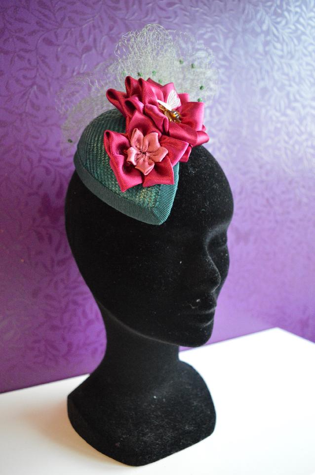 IMAGE - Dark green handblocked parasisal fascinator. Decorated with handfolded pink ribbon flowers and vintage netting, finished with a little bee. Fixes to the hair with wig clips.