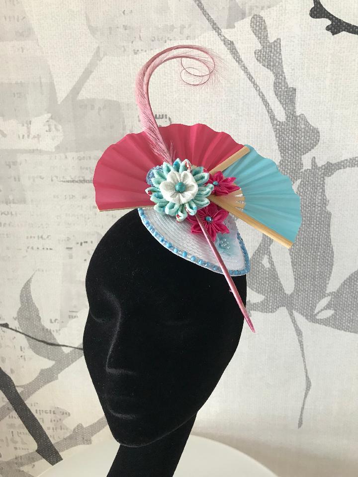 IMAGE - White straw fascinator with pink and blue paper fans. Decorated with pink feather and handfolded kanzashi flowers. The edge is finished with blue glass beads.
Fixes to the hair with a comb. The base is 11 centimeters wide.