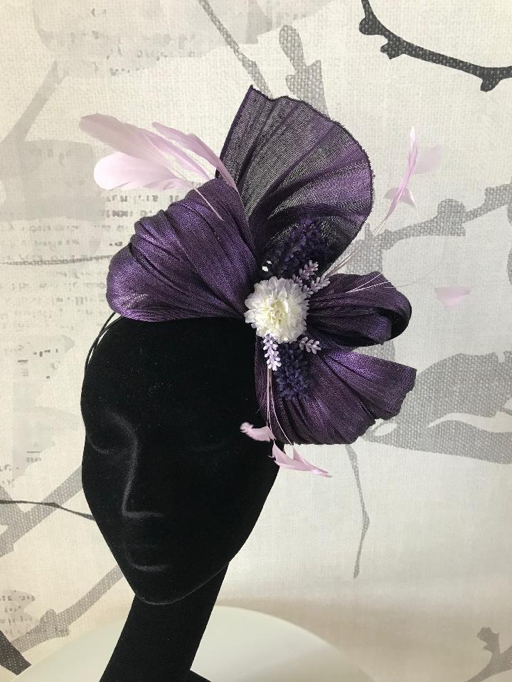 IMAGE - Purple swirl decorated with flowers and lilac feathers.
Stays on with a black headband. 
